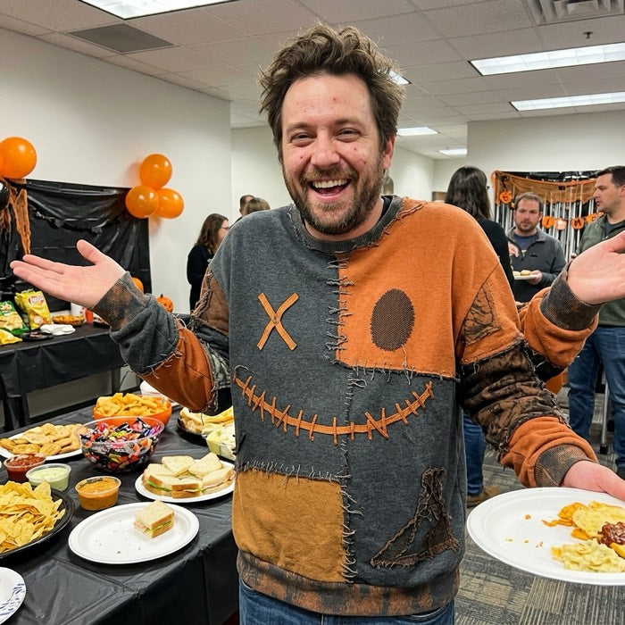 Man in an orange pumpkin jumper at an office Halloween lunch