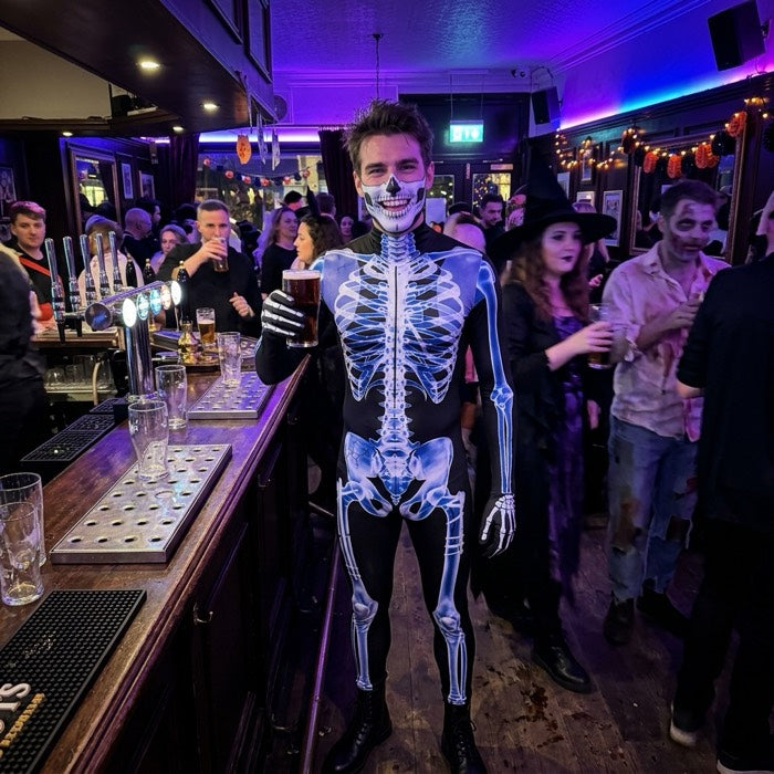 Man in a skeleton costume at a pub on Halloween night
